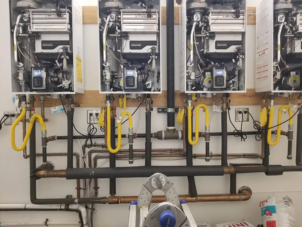 A bank of wall-mounted tankless water heaters with new gas and water piping