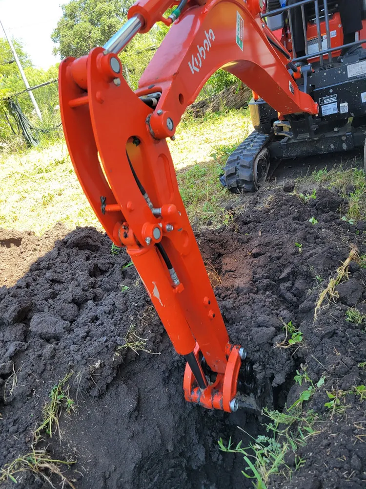 A mini excavator digging a trench for a sewer line replacement