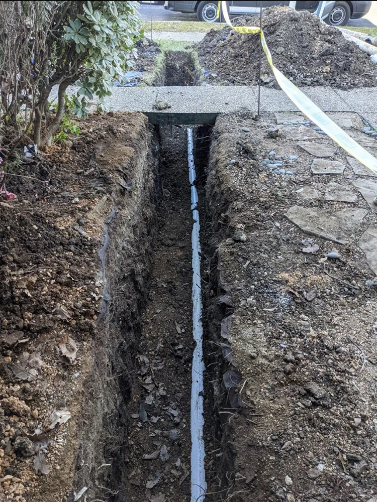 A long open trench exposing a sewer line in a San Antonio yard