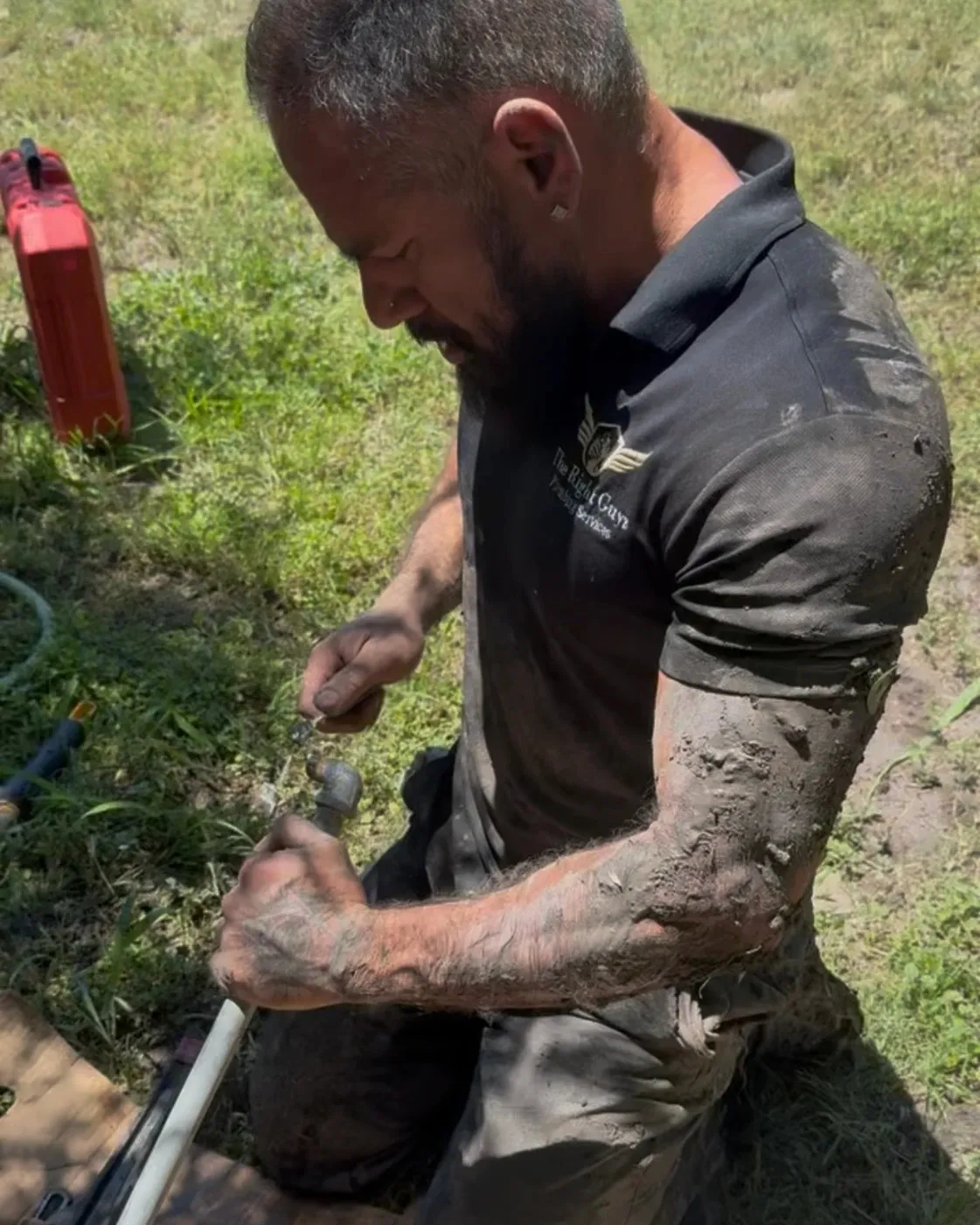 Tito Pacheco, dueño de The Right Guyz, arrodillado en un patio colocando una sección nueva de tubería de agua